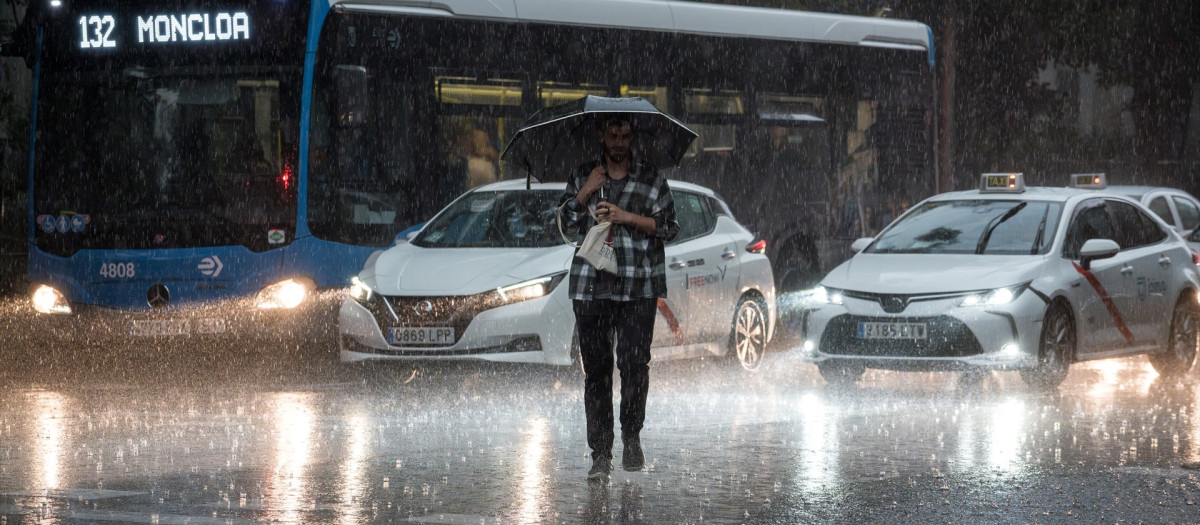 Una persona cruza la calle bajo la lluvia en Madrid