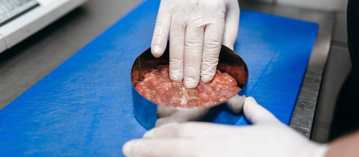 Un cocinero prepara un filete de hamburguesa