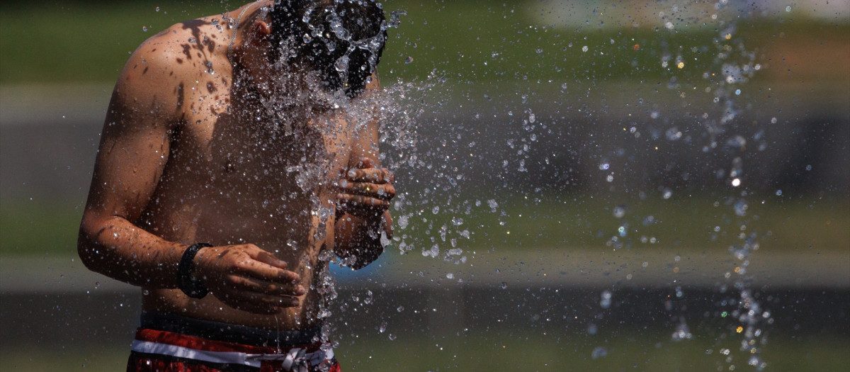 Un chico se refresca en Madrid Río