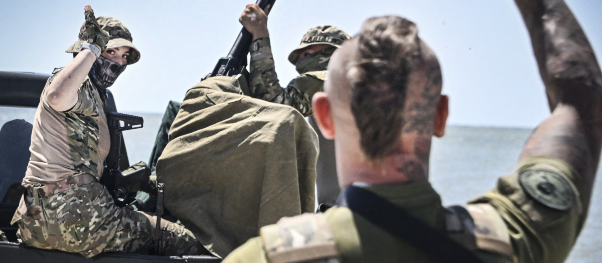 Volunteers of Espanola special force unit, a detachment of Russian football hooligans, greet each other having a training session at a training field in undisclosed location outside Mariupol on June 22, 2023. At the main football stadium in Moscow-controlled Mariupol, stickers of the local Ukrainian team are still visible, but armed football ultras from Russia now patrol the stands. A year after the port city fell to Moscow following a brutal siege, the stadium has a huge banner that reads "GLORY TO RUSSIA", with a Russian and Soviet flag flying over it. It has been covered in symbols of Russian football clubs -- from Moscow's CSKA to Saint Petersburg's Zenit. They were mostly brought here by football ultras who formed a fighting unit -- the "Espanola" -- to join Moscow's offensive. Based in Mariupol, they train on wild beaches on the Azov Sea outside the vastly destroyed city. (Photo by Alexander NEMENOV / AFP) / TO GO WITH AFP STORY "Russian ultras set aside soccer skirmishes to fight for Moscow" BY ANDREY BORODULIN