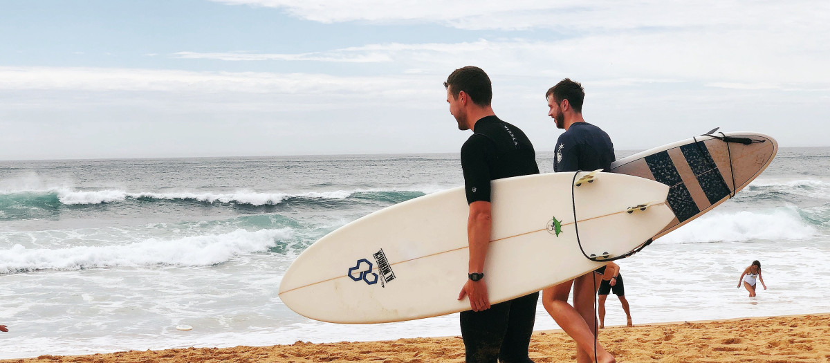 Dos jóvenes en la playa con sus tablas de surf