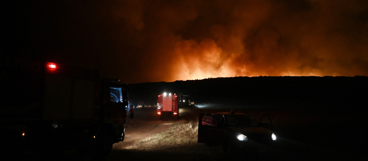 Vehículos de extinción de incendios con el fuego al fondo cerca de la ciudad de Volos, Grecia