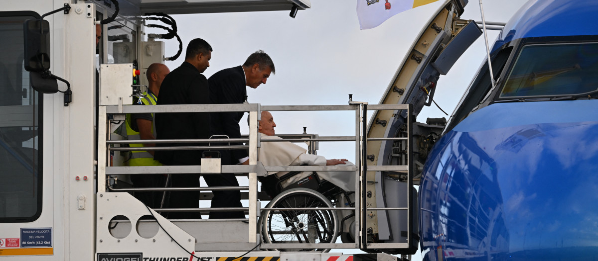 Pope Francis, seated on a wheelchair boards his plane on August 2, 2023 at Rome's Fiumicino airport, heading to the World Youth Day in Lisbon where a million youngsters from across the world are expected. (Photo by Andreas SOLARO / AFP)