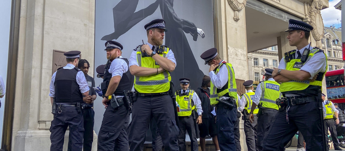 Agentes de policía registran a un joven a las puertas de una tienda de ropa en Londres