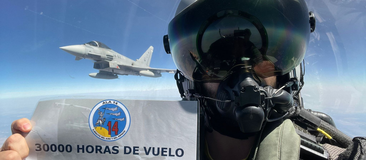 Un piloto muestra en pleno vuelo un cartel que acredita las 30.000 horas de vuelo de los Eurofighter en la base de Albacete