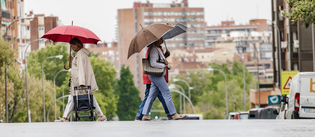 Varias personas caminan bajo la lluvia en Madrid