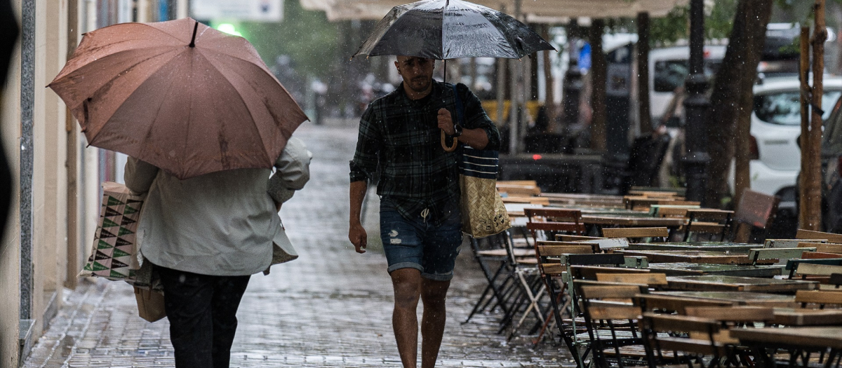 Varias personas se resguardan de la lluvia con paraguas