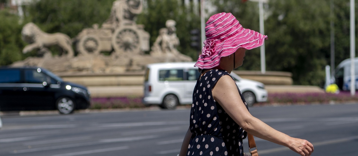 Una mujer pasea por una calle de Madrid con sombrero en pleno episodio de calor