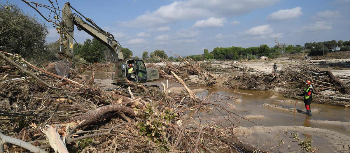 Una máquina excavadora y un trabajador durante el dispositivo de búsqueda de los desaparecidos por las lluvias de la DANA