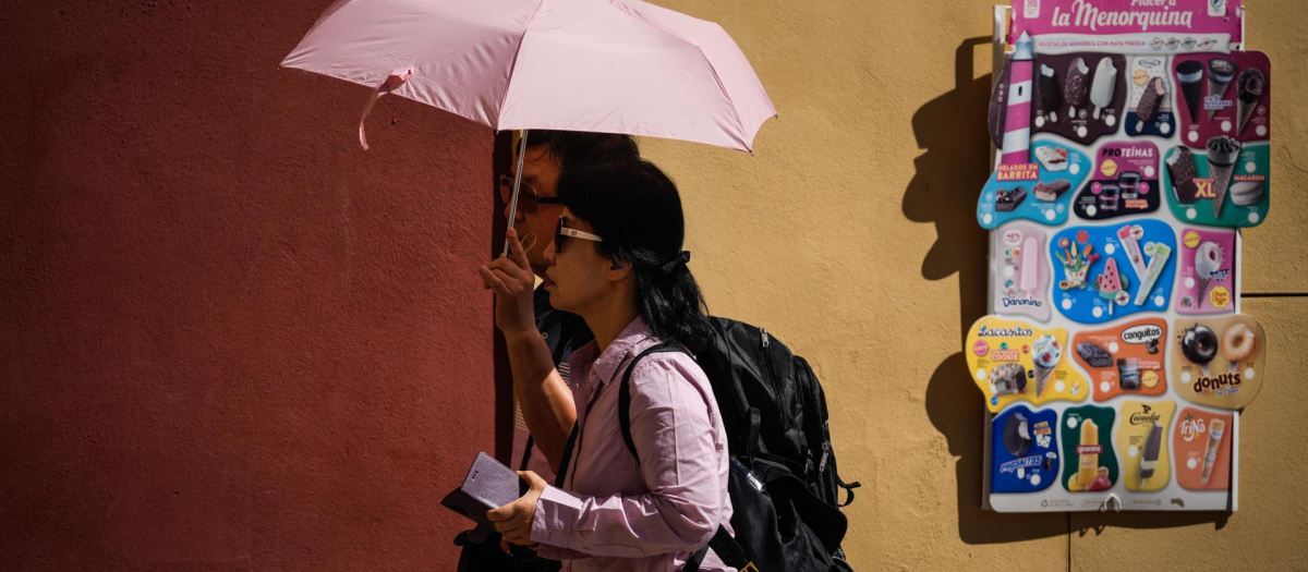 Una pareja de turistas pasea por la judería de Córdoba protegidos por un paraguas