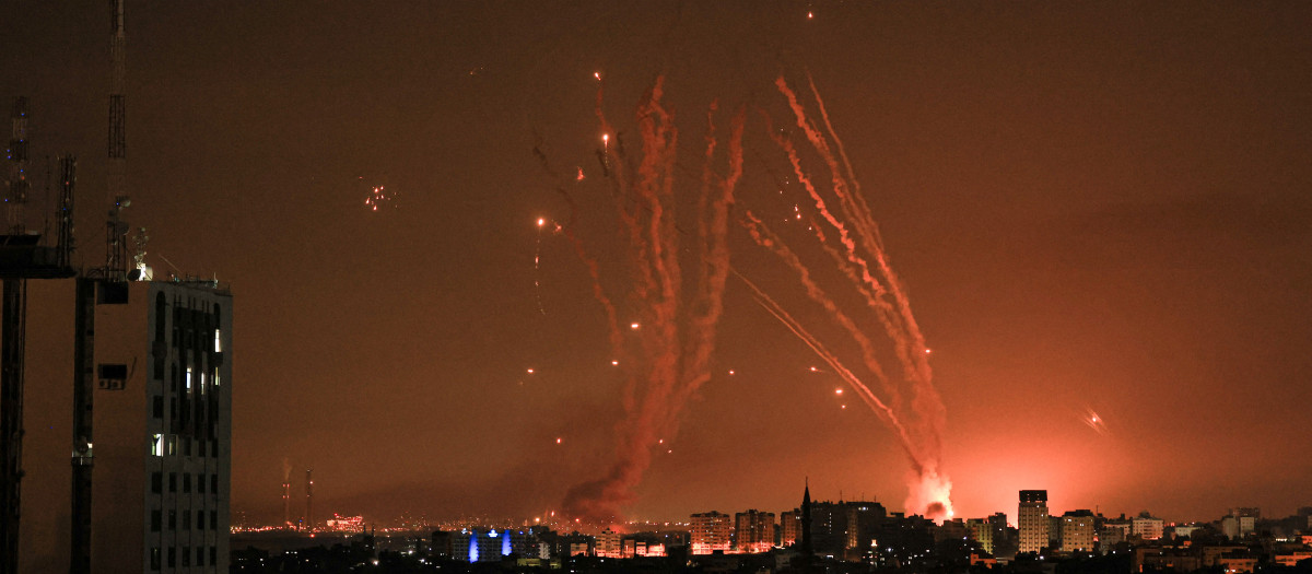 A salvo of rockets is fired by Palestinian militants from Gaza as an Israeli missile launched from the Iron Dome defence missile system attempts to intercept the rockets, fired from the Gaza Strip, over the city of Netivot in southern Israel on October 8, 2023. - Israel, reeling from the deadliest attack on its territory in half a century, formally declared war on Hamas Sunday as the conflict's death toll surged close to 1,000 after the Palestinian militant group launched a massive surprise assault from Gaza. (Photo by MAHMUD HAMS / AFP)