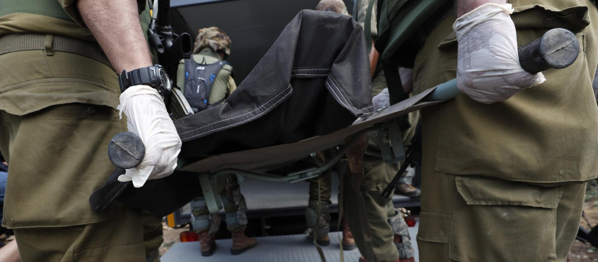 Soldados israelíes llevan los cuerpos de los israelíes asesinados en el kibutz de Kfar Aza, cerca de la frontera con Gaza