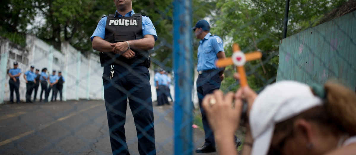 Una mujer sostiene una cruz frente a la cárcel de El Chipote