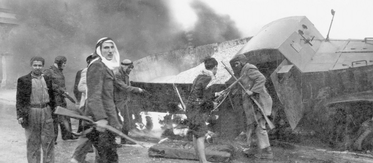 Irregulares palestinos cerca de un camión blindado de suministros de la Haganah quemado, en la carretera de Jerusalén, 1948