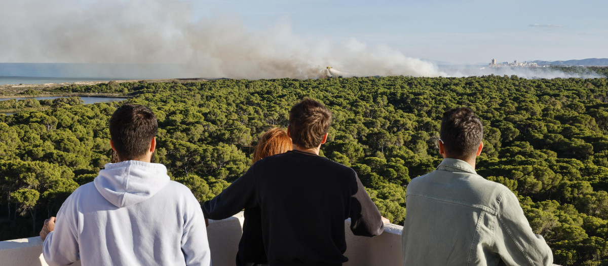 Varias personas contemplan las labores de extinción del último incendio en El Saler, Valencia