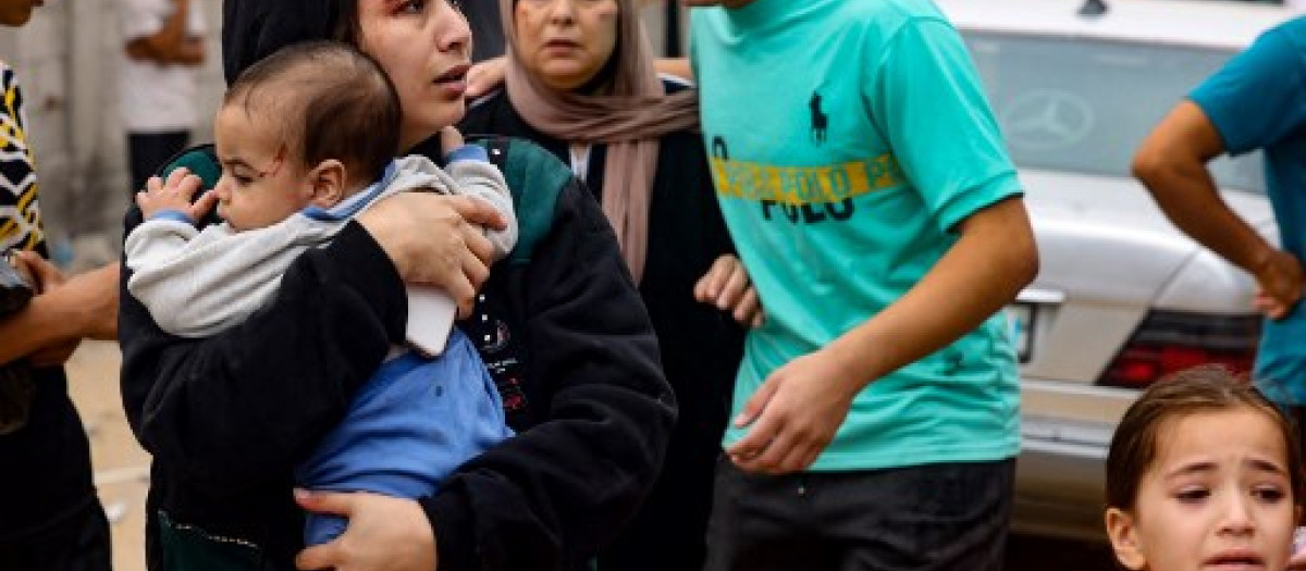 Una mujer herida lleva a su hija en la Franja de Gaza