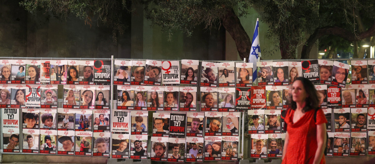 Una mujer pasa junto a retratos de rehenes israelíes en Tel Aviv