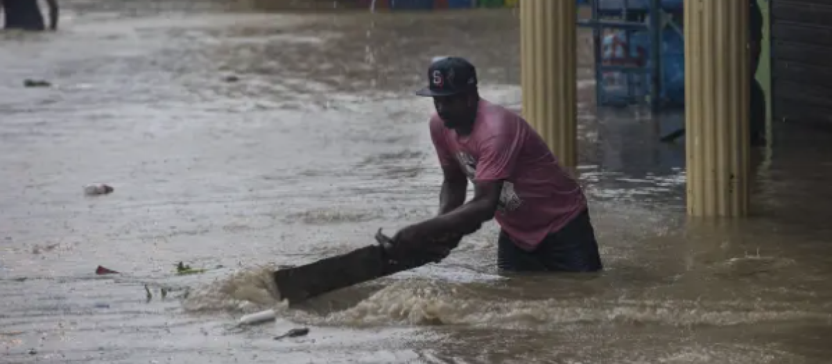 Un residente retira los restos en una calle inundada debido al paso de la tormenta tropical