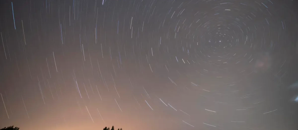 Fotografía de larga exposición durante la lluvia de estrellas de las Perseidas sobre la localidad cántabra de Comillas