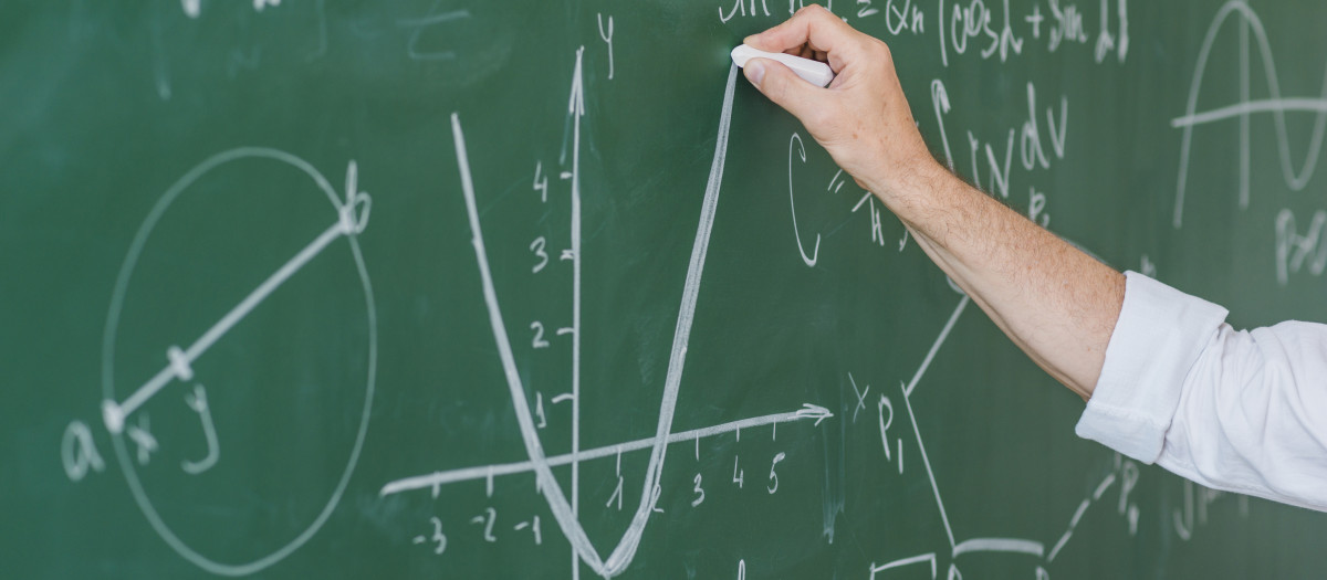 Una profesora utiliza la pizarra para resolver problemas matemáticos