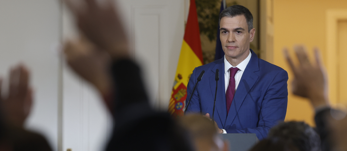 Pedro Sánchez mira las manos levantadas de los periodistas