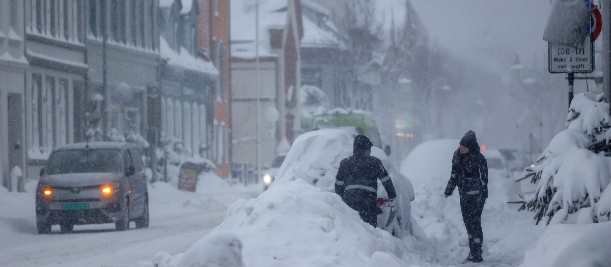 Dos personas quitan la nieve de un coche en la calle en Kristiansand, Noruega