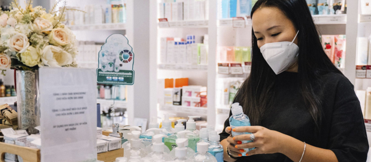 Una mujer con mascarilla mira un producto en una farmacia