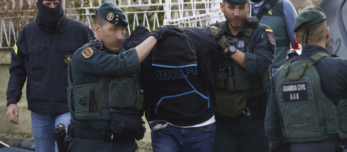 Agentes de la Guardia Civil y de los Mossos d'Esquadra custodian a uno de los detenidos en Martorell (Barcelona)