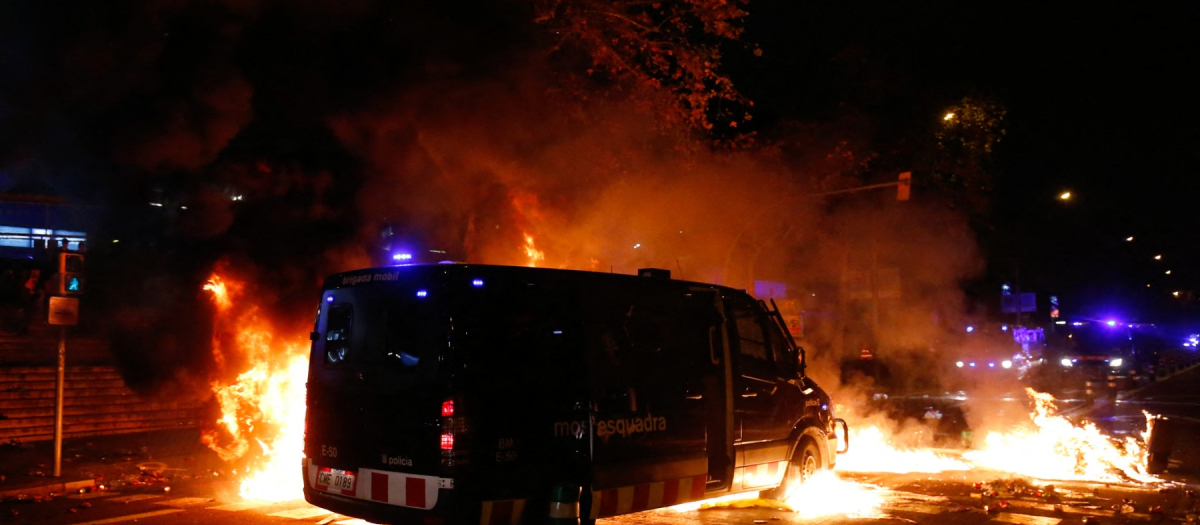 Una lechera de los Mossos D'Esquadra se abre paso entre contenedores quemados por los independentistas de Tsunami