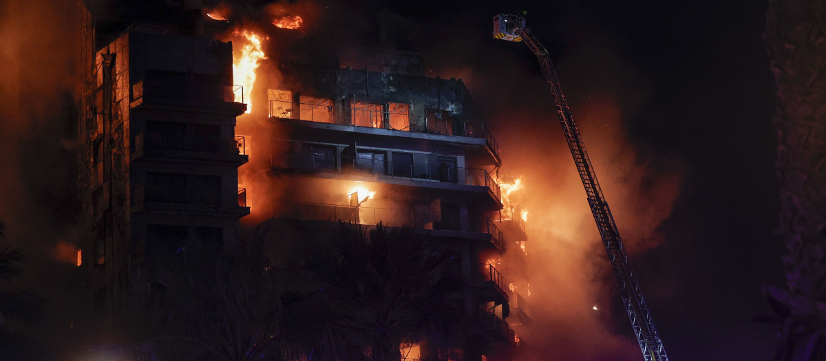 Vista del incendio declarado sobre las cinco y media de esta tarde en un quinto piso de un edificio de viviendas de València que ha afectado totalmente al inmueble y se ha propagado a otro anexo, y los bomberos intentan aún rescatar a vecinos desde los balcones.