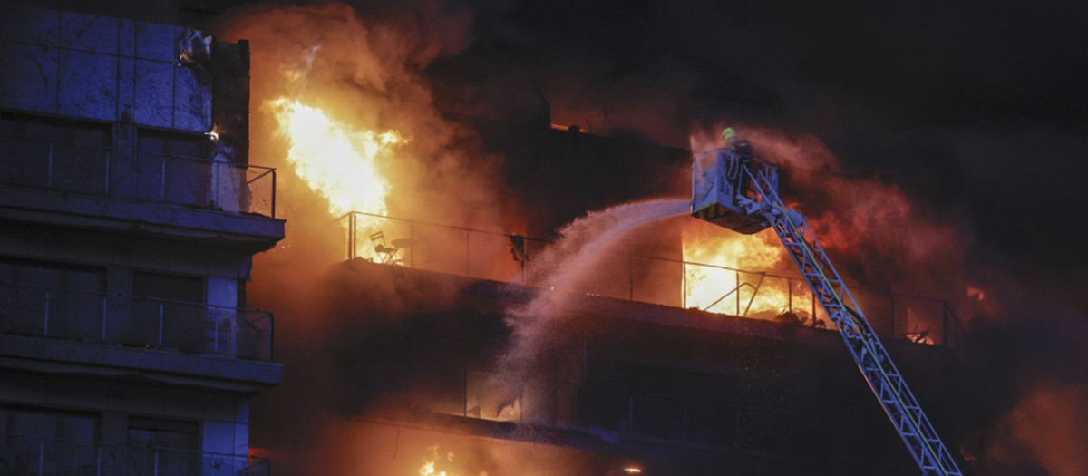 Un bombero subido a una escala lucha contra las llamas en el edificio devorado por las llamas en Valencia