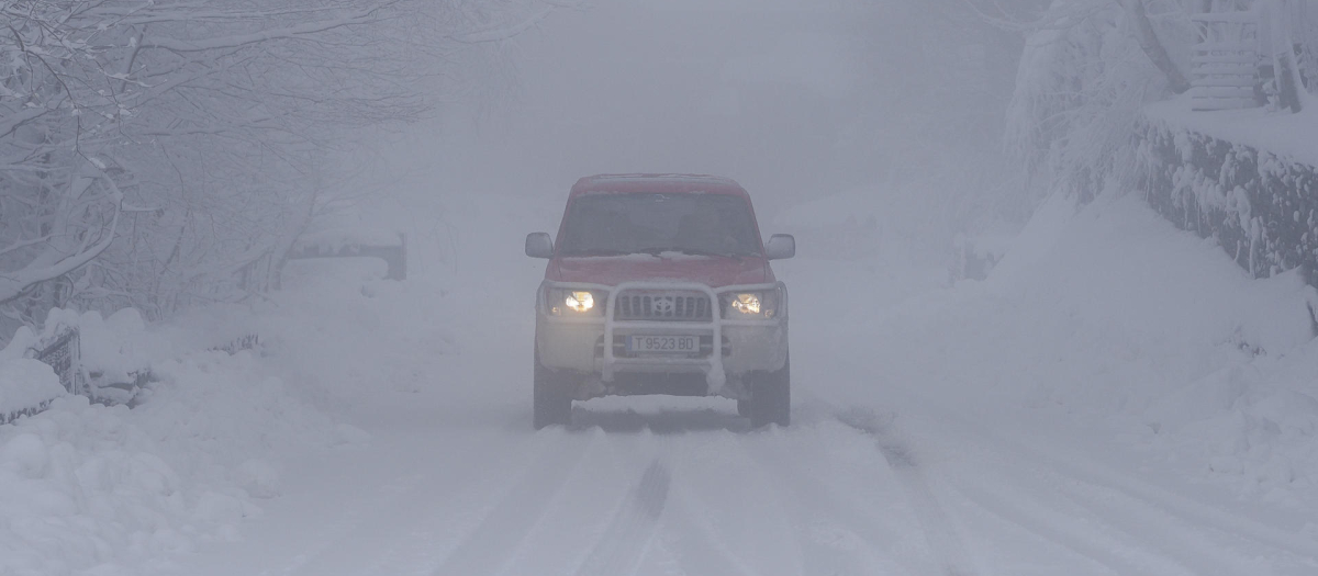 Un vehículo circula por una carretera cubierta de nieve este lunes en O Cebreiro, Lugo