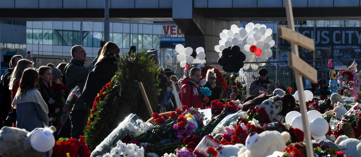 La gente lleva flores a un monumento improvisado frente a la incendiada sala de conciertos Crocus City Hall