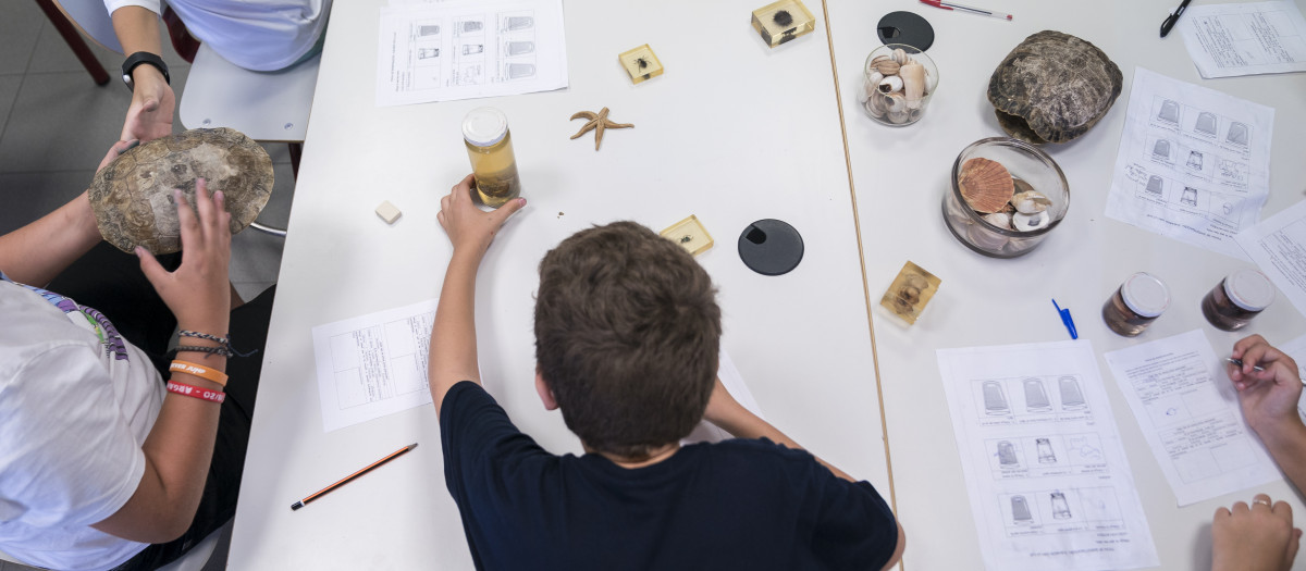 Un niño en una mesa de un aula con distinto material escolar