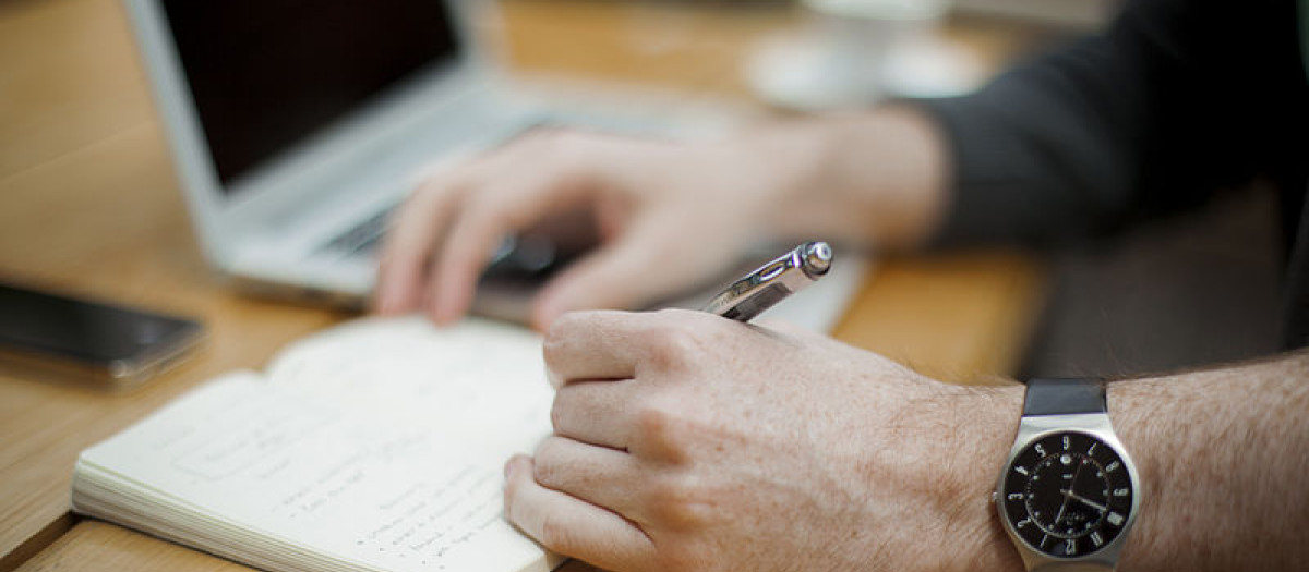 Una persona zurda escribe en una libreta