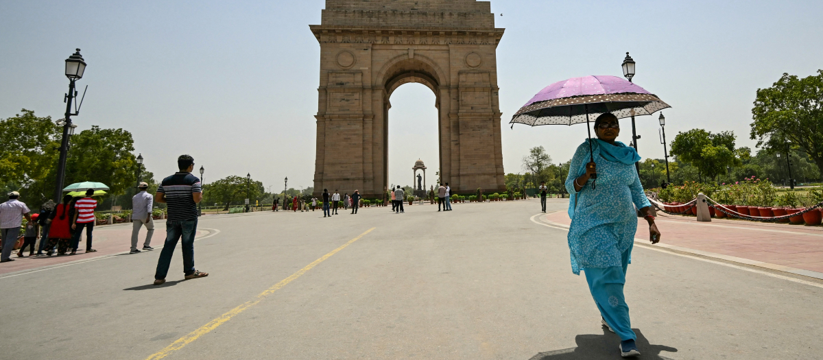 Una mujer sostiene un paraguas cerca de la Puerta de la India durante una severa ola de calor en un caluroso día de verano en Nueva Delhi