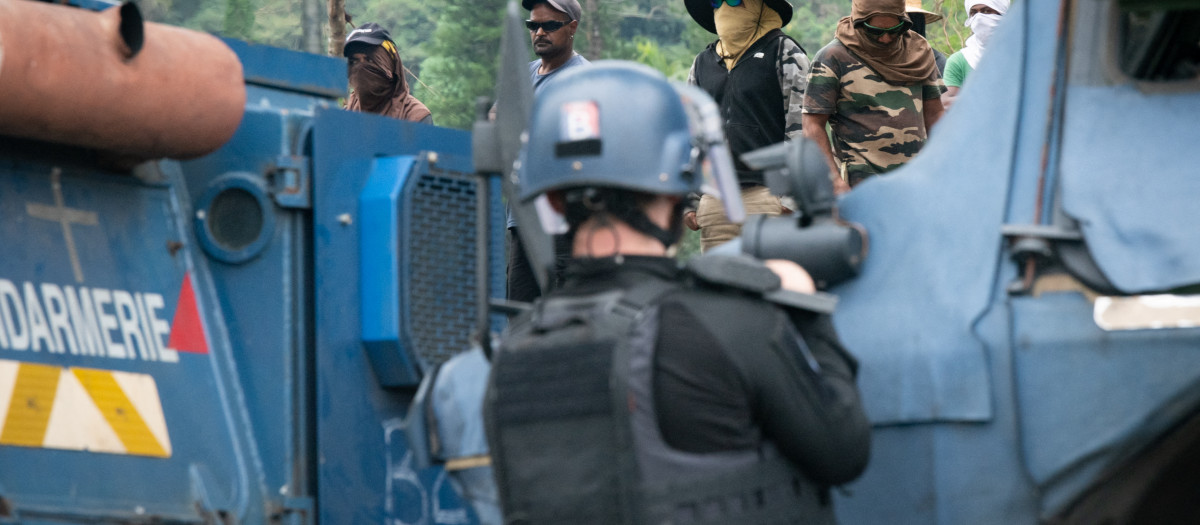 Un gendarme francés detrás de un vehículo blindado Berliet VXB-170 frente a activistas