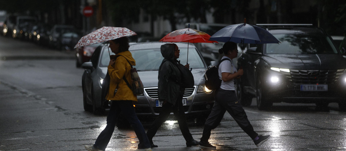 Varias mujeres cruzan la calle bajo la lluvia en Madrid este lunes