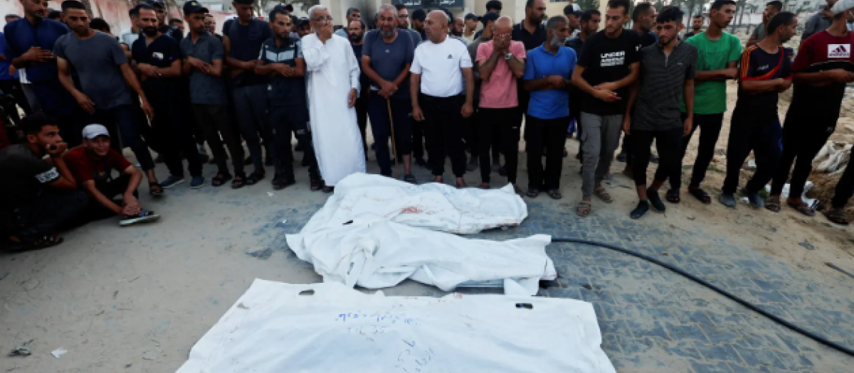 Un grupo de palestinos junto a cadáveres de víctimas del ataque israelí a un campamento de Al-Mawasi este viernes