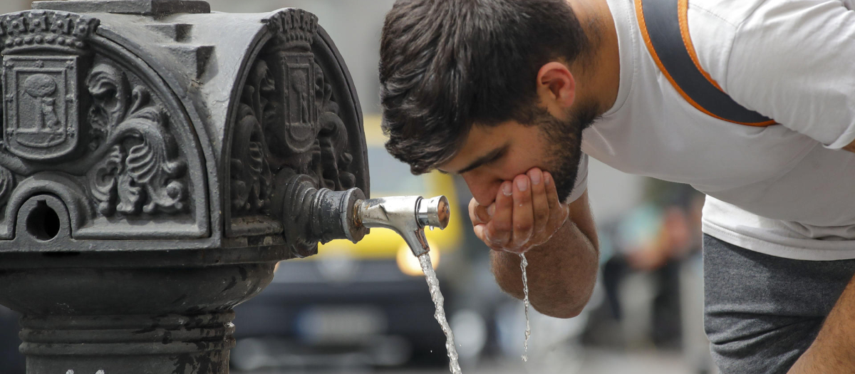Un hombre bebe agua en una fuente pública del centro de Madrid