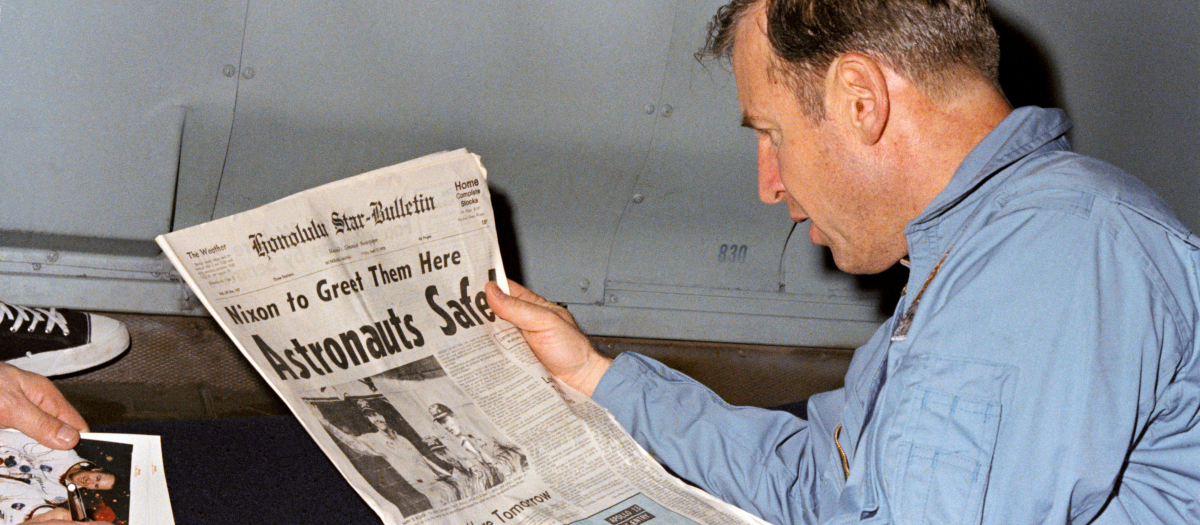 El astronauta James A. Lovell Jr., comandante de la misión del Apolo 13, leyendo un reportaje de un periódico sobre su exitosa recuperación de una misión plagada de problemas