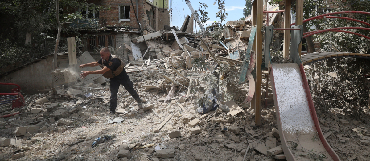 Un rescatista ucraniano limpia los escombros de un edificio residencial destruido tras un ataque con misiles en Kiev