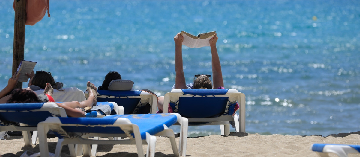 Varias personas leen y toman en sol en Mallorca