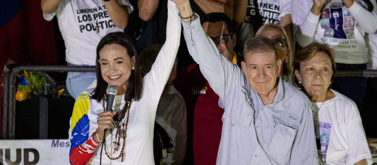 AME4966. CARACAS (VENEZUELA), 25/07/2024.- La líder opositora venezolana, María Corina Machado (i), y el candidato a la presidencia de Venezuela, Edmundo González Urrutia (c), saludan a simpatizantes en el cierre de campaña de González Urrutia, este jueves, en Caracas (Venezuela). González Urrutia pidió a los venezolanos, en un acto de clausura de la campaña electoral, votar el domingo para comenzar el camino de la "reconciliación nacional". EFE/ Ronald Peña R.