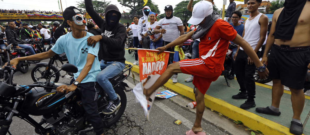 Un manifestante patea una pancarta de campaña del presidente venezolano Nicolás Maduro durante una protesta en Valencia, estado Carabobo, Venezuela