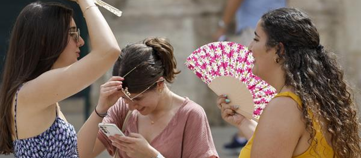 Tres personas se protegen del calor con abanicos en Valencia