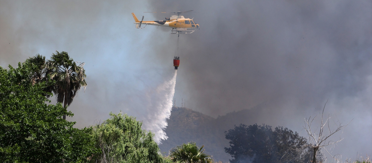 Un helicóptero echa agua a una zona afectada por un incendio