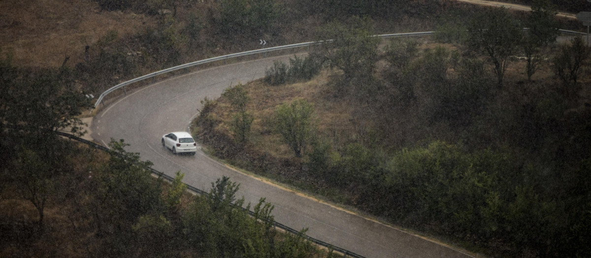 Un vehículo circula este martes bajo un fuerte aguacero por una carretera cercana a la localidad castellonense de Morella