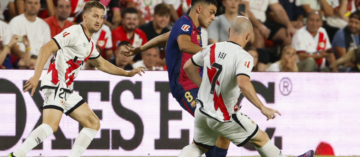 El centrocampista del Rayo 'Isi' Palazón (d) presiona al centrocampista del FC Barcelona Pedri (c) durante el partido de Liga en Primera División que Rayo Vallecano y FC Barcelona disputan este martes en el estadio de Vallecas, en Madrid