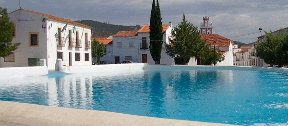 El agua color turquesa de la alberca destaca entre el blanco de las construcciones cercanas